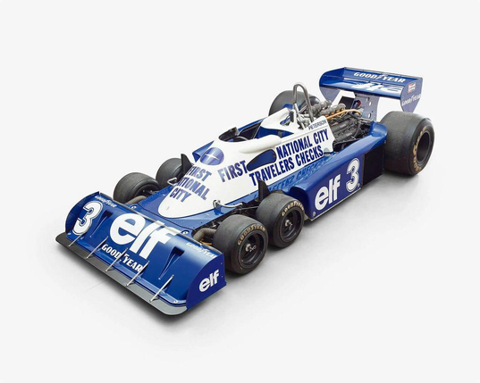 A vintage Formula 1 car in blue and white, featuring sponsor logos. It showcases a distinctive three-wheeled design and sleek aerodynamic shape.
