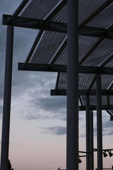 un bout de toit de préau non régulier qui forme un « escalier » circulaire sur le ciel du soleil couchant, avec les poteaux de soutiens