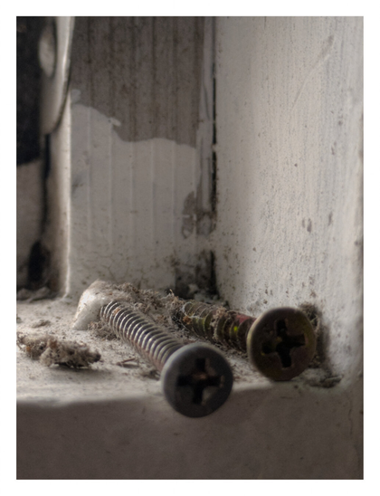 Two screws resting on a windowsill.