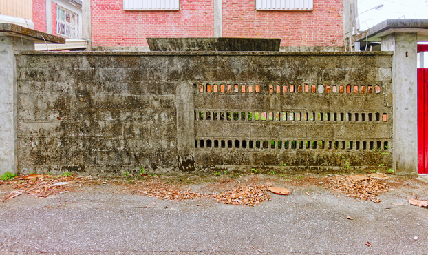 Front yard wall with three rows of niche-like holes, the top row holes filled with what looks like bricks.