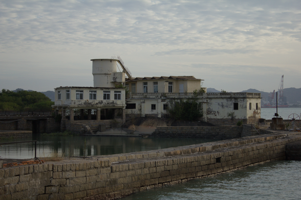 a run down, old concrete building by the water.