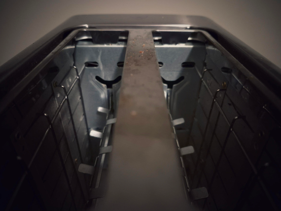 Looking at the short side of a two-slice toaster, where a smiling ‘face’ can be seen: the two mounting slots for the heating elements as eyes and the semicircular slot where the lever holds the toast as a smiling ‘mouth’.