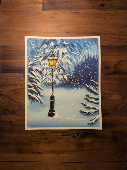 This is a watercolor landscape painting in portrait orientation on an 8x10 sheet of Arches Coldpress watercolor paper. This painting features a lamp post with evergreen trees covered in snow in the background and foreground with a dark area to the right suggesting a path beyond the trees. The yellow orange light of the lamp post stands out against the blues and whites in this painting.