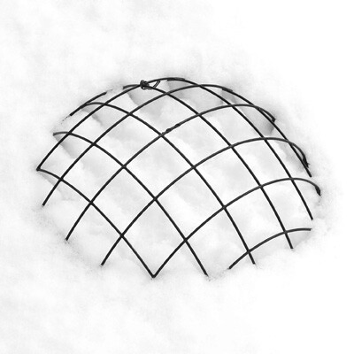 白い雪の中に、上半分だけが露出した黒い半球状の金網のモノクロ写真。金網の規則正しい格子模様が、周囲の雪の白さによって強調されている。