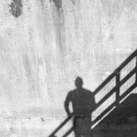 A black-and-white film photo. A solitary figure is cast onto the concrete wall of the hydro station in Gonzales, Texas. Saturday, December 6, 2025.