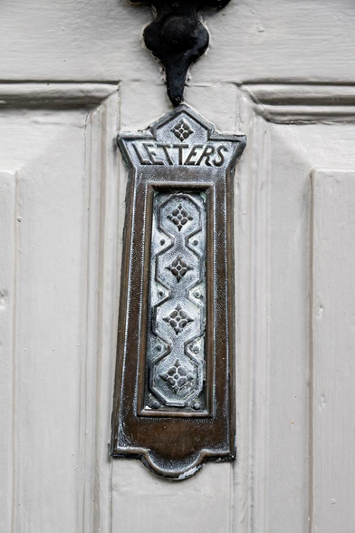 Ornately moulded old brass letter box in the front door of a house in Topsham, SW England