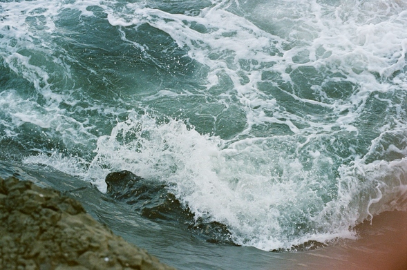 close up color photograph of waves churning and crashing against rocks