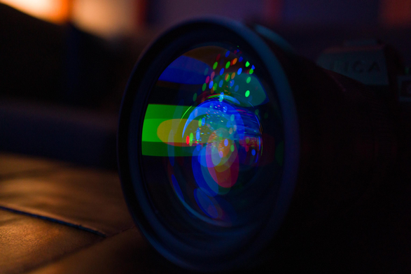Reflection of a Christmas tree and the colorful lights in the lens of a camera.
