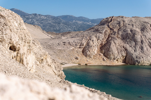 Grey mountains composed of limestone rocks, there is a bay and the sea.