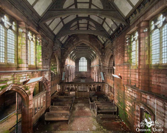 An abandoned church interior features weathered pews and stone walls, showing decay. Sunlight streams through arched windows,