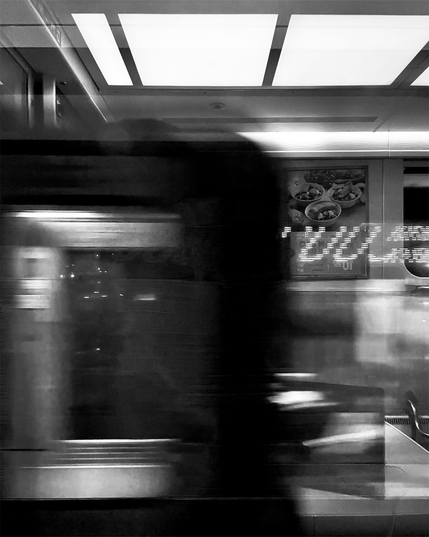A blurred figure of a passing train, featuring vibrant reflections of advertisements.