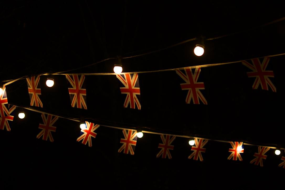 UK Union Flag bunting intertwined with lights. All of this is against a black sky