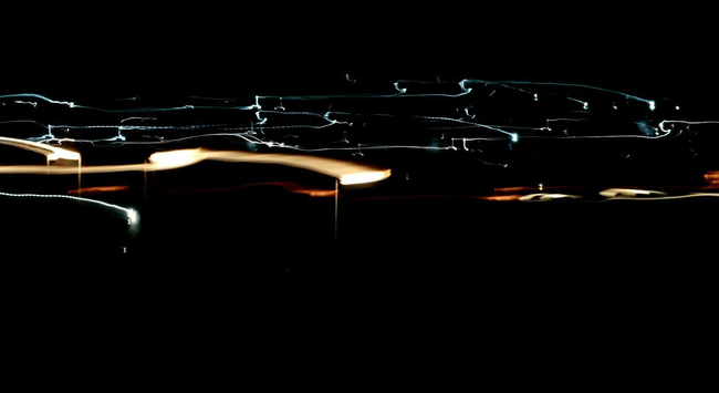 Landscape aspect ratio: Medium exposure light trails against a black background suggesting street light tops.
Yellow-white street light trails. Orange patches of light illuminating patches of ground with swirling lateral and horizontal dotted tungsten blue trails above.