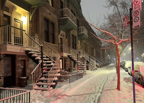 Snow-covered street, view down sidewalk curved staircases on left, cars on right, all snow-covered.