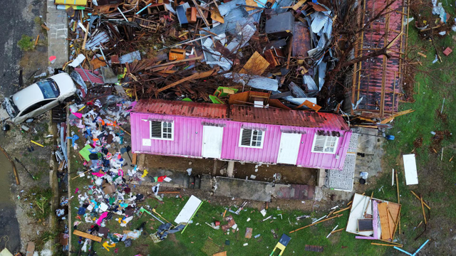 A drone view of damage caused by Hurricane Melissa, with a pink facade house in the centre.