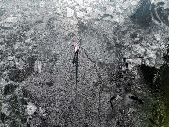 A drone view shows a man surfing with the wing on the frozen Kierskie lake.