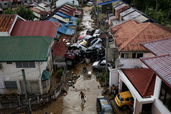 A drone view shows a man crossing a muddy street where cars piled up after being swept away in floods brought on by Typhoon Kalmaegi.