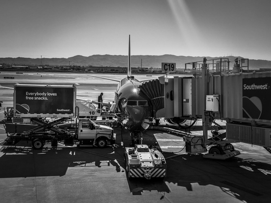 A Boeing 737 plane is parked at a gate with ground service vehicles surrounding it at an airport.