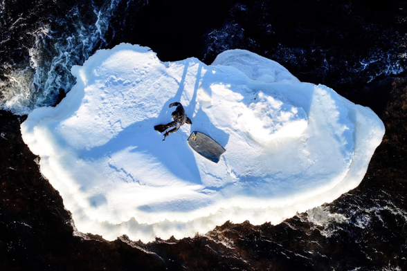 A man tows his boogie board towards a standing wave across an ice pack on the St. Lawrence River.