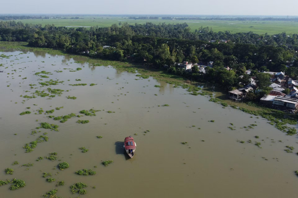 A drone view of a floating school, built aboard a boat, travels down a river.
