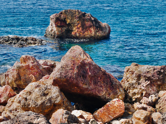 Photo de roche rougeâtre dans la mer bleu 

Photo of reddish rock in the blue sea