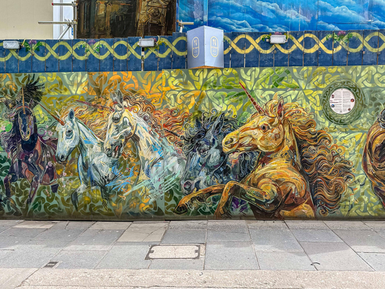 Baustellenverkleidung mit künstlerisch gemalten Pferden.