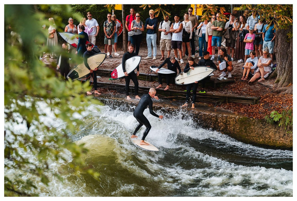 Ein Surfer surft die Eisbachwelle im Englischen Garten München.