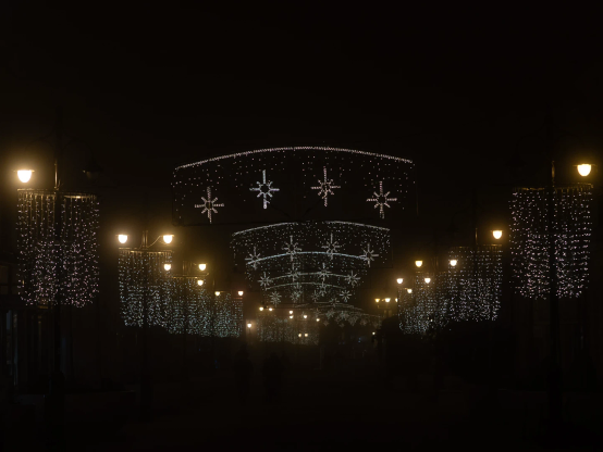 Fußgängerzone, nachts. Warm weihnachtsbeleuchtet, der Rest liegt im Dunkeln.