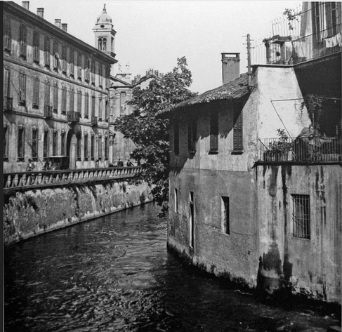 Vecchia foto in bianco e nero di Milano con un tratto di Naviglio e vecchie case