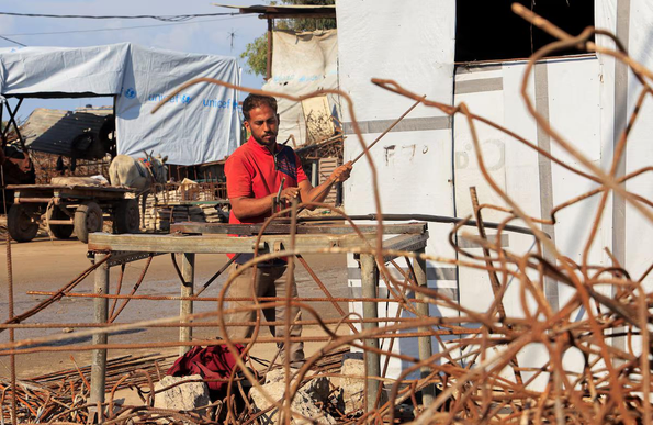 A Palestinian worker reshapes and straightens steel bars recovered from destroyed homes using basic tools inside a small workshop, amid a severe shortage of construction materials, in Khan Younis, southern Gaza Strip, December 10, 2025. REUTERS/Haseeb Alwazeer 