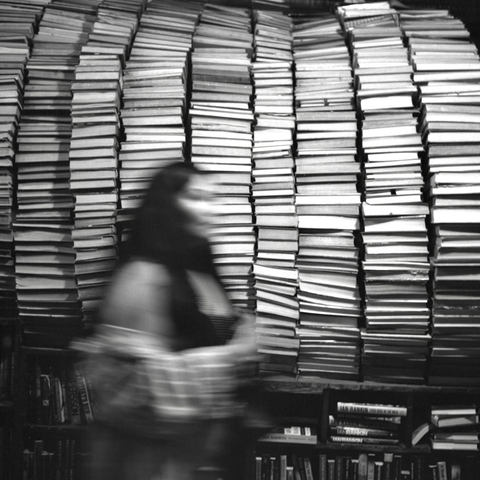 A black-and-white film photo. A woman walks by the Tunnel of Books at The Last Bookstore in downtown Los Angeles, California. Sunday, May 18, 2025.