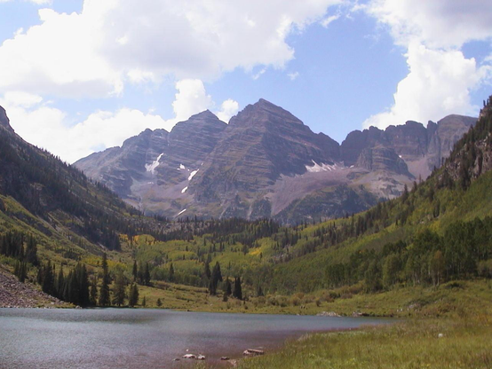 A picture of the Maroon Bells outside of Aspen, Colorado.  Part of Crater Lake can be seen in the foreground.  There isn't much snow on  the Maroon Bells (just a few slivers of snow can be seen).