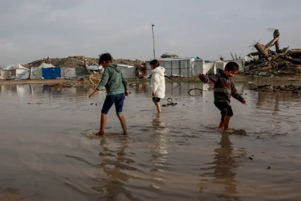 Palestinian children wade through water.