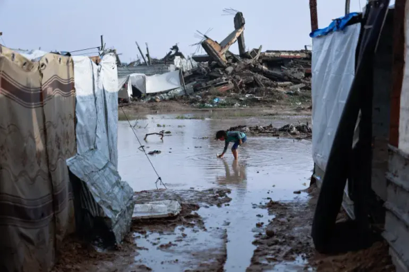 Palestinian children wade through water.