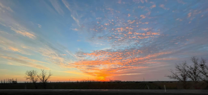 A colorful sunset with lots of orange color on wispy clouds in the sky.