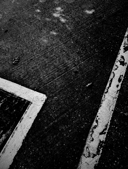 A black and white photo showing a cropped overhead view of some lines painted on pavement.