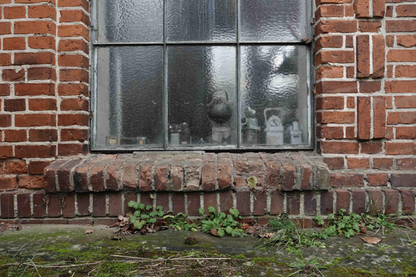 Fenster mit Metallrahmen und Sprossen in einer Ziegelwand. Digitale Farbaufnahme.