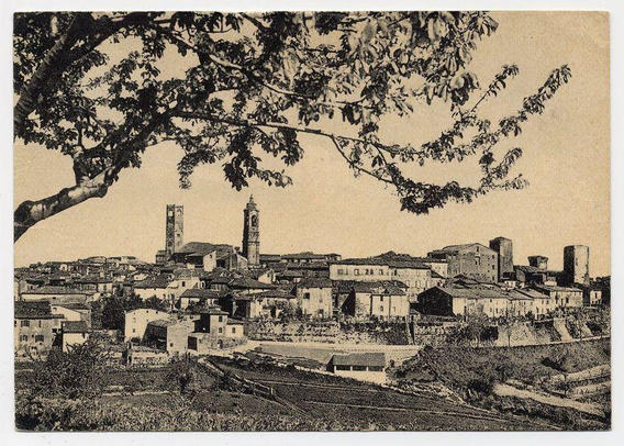 The image depicts a black and white photograph of an old European town. The view is from above, showing the rooftops in various shades of gray against what appears to be a pale sky or background. Prominent features include tall buildings with pitched roofs, some featuring tower-like structures that could suggest historical significance, such as churches or municipal centers.

In the foreground, tree branches partially obscure parts of the townscape, creating depth and framing effect on the view below. The foliage is detailed, suggesting it might be from a species commonly found in temperate climates. This adds texture to the image and implies an older season when trees have more leaves.

The overall impression given by this photograph suggests history and tradition within the community depicted here; perhaps even something akin to a medieval European town with its old stone buildings and communal spaces where people might gather for social interaction or events.

There is no visible movement, indicating that it could be capturing still moments of daily life in such settings. The absence of modern elements reinforces this historical ambiance. There are also indications of vegetation around the lower part of the image which may suggest agricultural practices nearby, common within European countryside towns.
