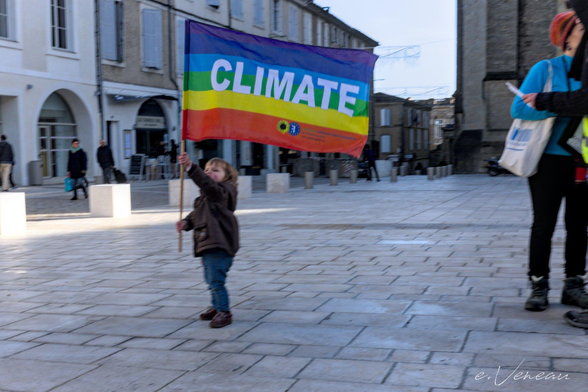 A child waves a rainbow flag with the slogan 'climate'