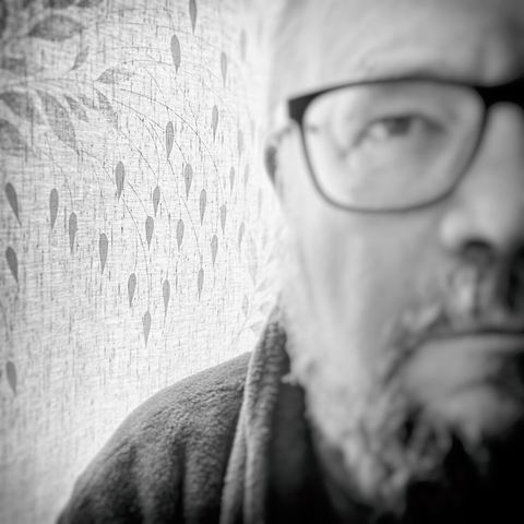 A close-up view of a person wearing a cozy robe, set against a textured wall adorned with subtle leaf patterns.