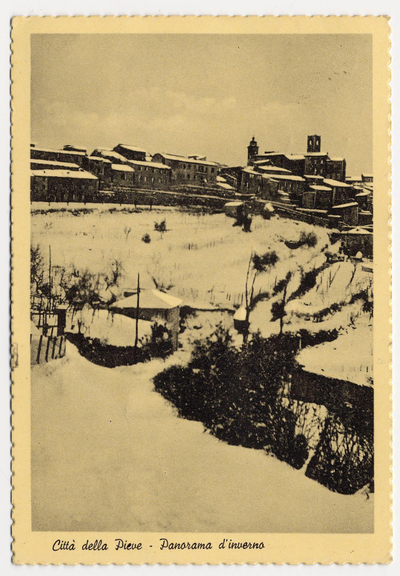 The image depicts a sepia-toned photograph of Città della Pieve, as labeled in the lower left corner. The setting appears to be winter, with snow blanketing the ground and covering rooftops of buildings visible across an expanse that may represent a river or canal. Trees without leaves are seen along what could be a path through the snowy landscape. In the background is a cluster of architectural structures indicative of historical European urban planning, including multi-story residential or institutional buildings and at least one prominent tower with a conical roof. The overall condition suggests an aged photograph, likely from the late 19th to early 20th century judging by its style and quality.