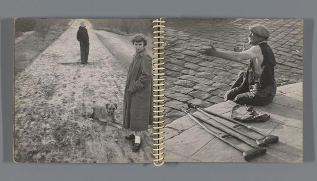 The image shows two black and white photographs side by side in a spiral-bound notebook. On the left page, there's an outdoor scene with three individuals: one woman standing on what appears to be a dirt path wearing a coat, skirt, shoes, and socks; next to her is a dog sitting down looking towards the camera; behind them stands another man also dressed warmly but facing away from the viewer. The right page features two men outdoors as well; one seated with crutches beside him while gesturing outwardly, perhaps in conversation or addressing someone not visible within this frame; and standing up is an older gentleman wearing a cap, jacket, trousers, shoes, and socks. Both sets of individuals seem to be engaged in everyday activities without direct interaction with the photographer's presence. The environment suggests cold weather given their attire.