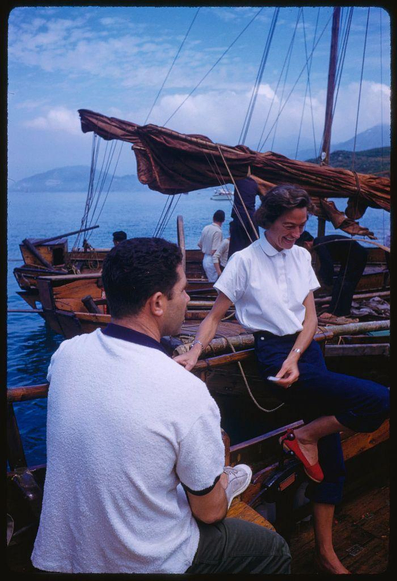 two people sitting on a boat with water and mountains behind them