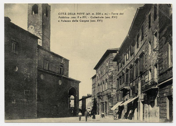 The image is a sepia-toned historical photograph depicting an urban scene from Città della Pieve, Italy. It appears to be taken during the early 20th century or late 19th century based on its style and content. The street scene shows buildings with European architecture such as stone facades, arched doorways, and shuttered windows typical of historic town centers.

In the foreground, a group of people can be seen walking along the narrow street, giving scale to the environment and suggesting daily life in this setting. To the left is an imposing brick tower labeled "Torre del Pubblico," indicating it might have been used for public administration or as part of a municipal structure during its time.

To the right stands another significant building with architectural details characteristic of medieval structures, identified by text on top of the image: "Città della Pieve" and references to various historical periods including early 1508 AD ("alt. m. 508 s. m."). The words suggest that this photograph is documenting notable sites in Città della Pieve.

The background features a large archway, possibly part of an ancient gateway or bridge known as "Palazzo della Corgna," which could be another historical site or administrative building within the city. Above the scene, text provides additional context about specific landmarks associated with their respective periods (XVI for [...]