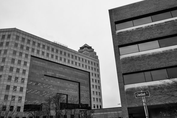 Black and white image of downtown Des Moines, Iowa with the top of 801 Grand visible in the background and a street sign reading Chestnut Street in the foreground. 