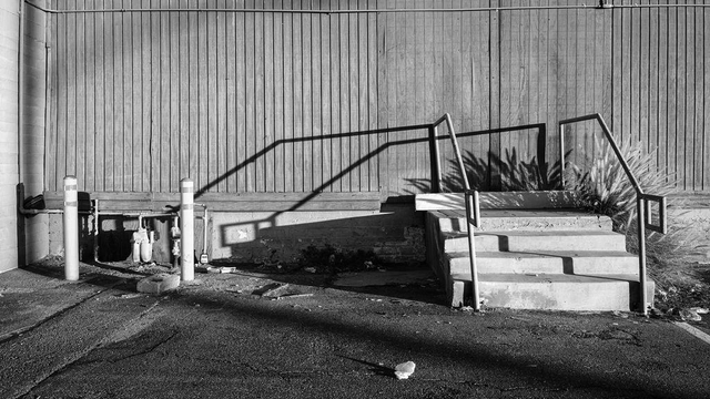 A crooked concrete staircase leads to a blank wall.