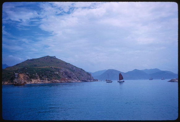 a body of water with sailboats and a hill nearby