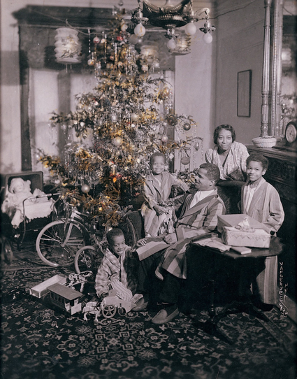 A vintage photo of a black family, Christmas morning, everyone looks very happy. Mom, dad, three kids, presents under the tree. 