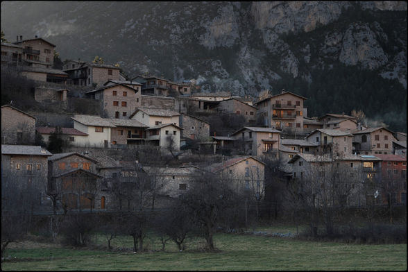 CAT
Sense fer soroll, gens ni mica
les cases ja gairebé dorment.
La tarda cau damunt les teulades.
Bocins i visions d'infantesa
fan pessigolles al magí
Fred i fum i tot una mica gris

OC
Sens far de bruch, pas brica
los ostals son gaireben endormits.
L'après-miègjorn tomba suls teulats.
Còrns e visions d'enfança
coquilhatz l'esperit
Fred e fum e tot un pauc gris
