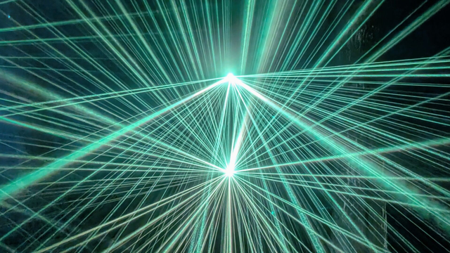 Two sets of green light beams, one above the other, enjoy in a star pattern, causing intersecting patterns to form.